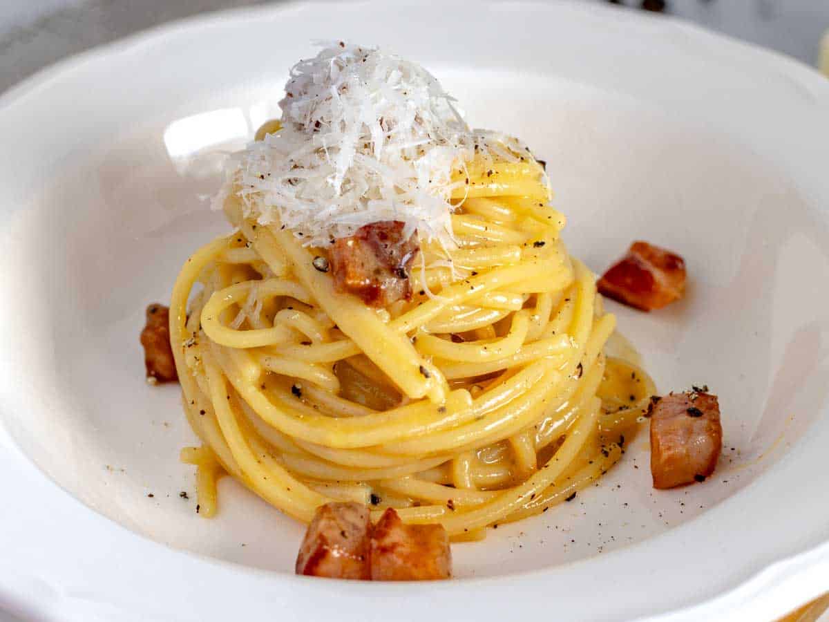 Spaghetti carbonara in a rustic white plate with pecorino cheese