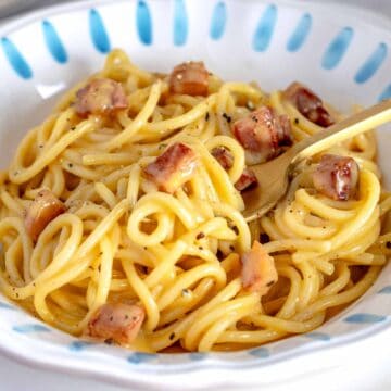 Carbonara with a golden fork and guanciale