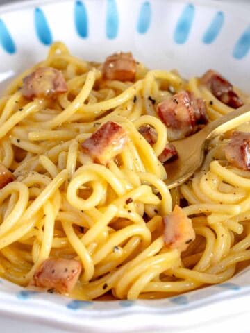 Carbonara with a golden fork and guanciale