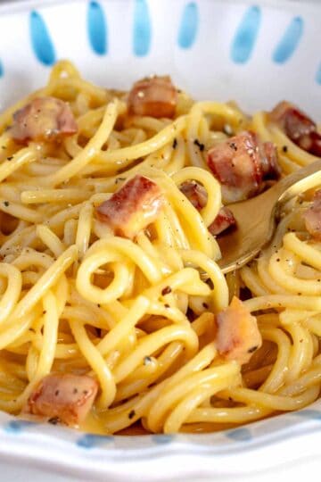 Carbonara with a golden fork and guanciale