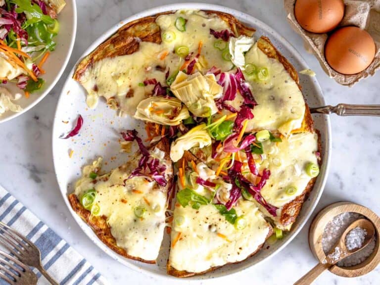 Frittata topped with melted cheese and artichoke salad