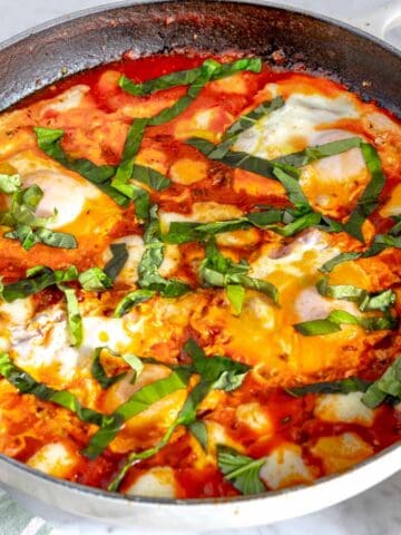 eggs in purgatory in a shite skillet with basil