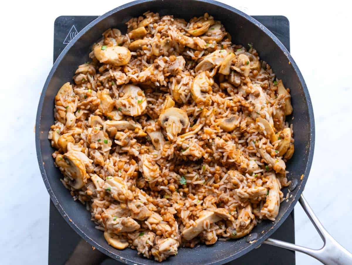 Step 4 adding lentils rice chicken and sauce to the skillet and mixing all.
