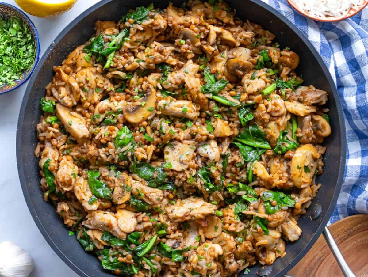 Step 5 stirring fresh spinach into Mediterranean chicken rice mixture.