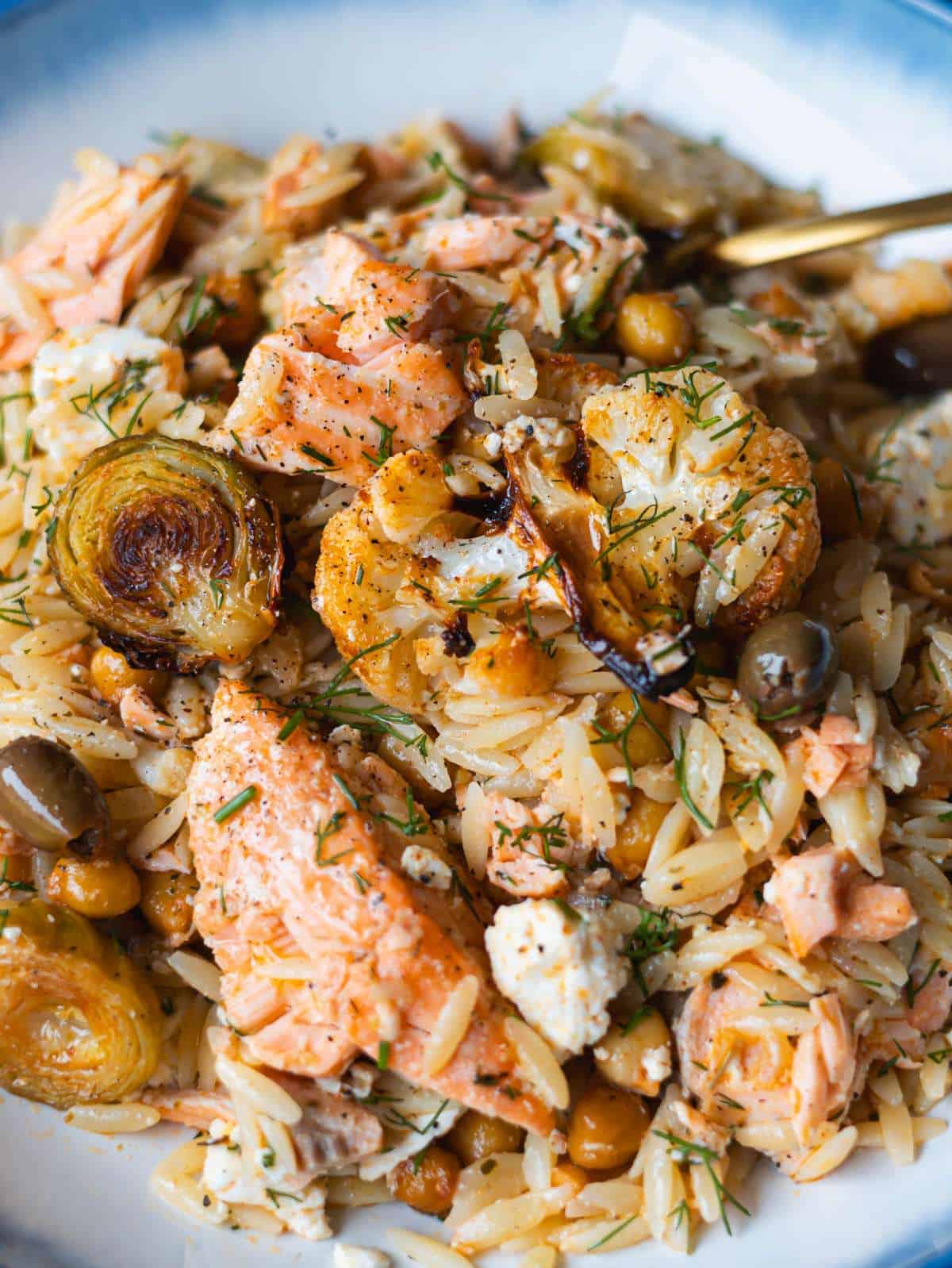 Close up sheet pan salmon orzo with flaky salmon feta and roasted vegetables.