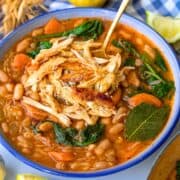 Rustic Greek chicken and bean stew served in a blue bowl with bright Mediterranean flavors.
