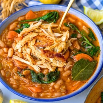 Rustic Greek chicken and bean stew served in a blue bowl with bright Mediterranean flavors.