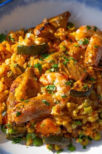 Shrimp paella cooked on a sheet pan with vegetables rice and served in a bowl.