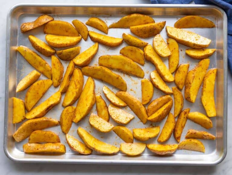 Step 1 Potatoes tossed with oil and paprika arranged on a baking sheet before roasting.
