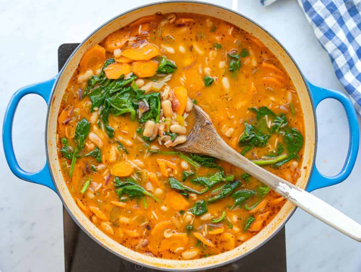 Step 4 Stirring fresh spinach into the pot to wilt into the hot stew.