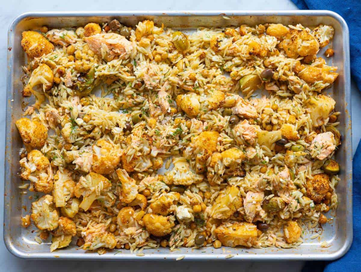 Step 4 Tossing cooked orzo with salmon and roasted vegetables on sheet pan.