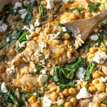 Bright skillet of lemon chicken orzo with creamy spinach, chickpeas and golden chicken on top.