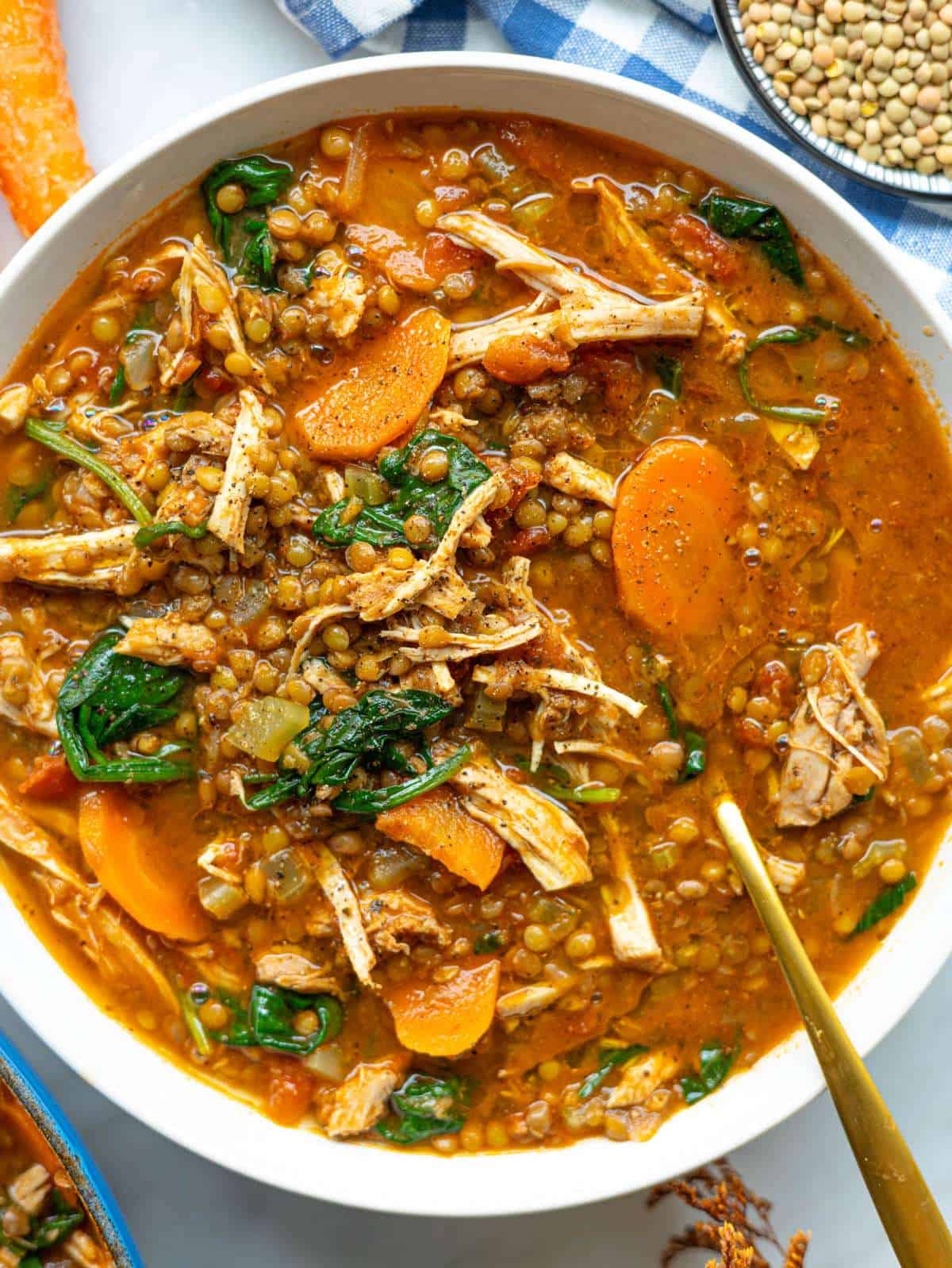 Finished chicken lentil soup served in a bowl with spinach and vegetables in a rich tomato broth.