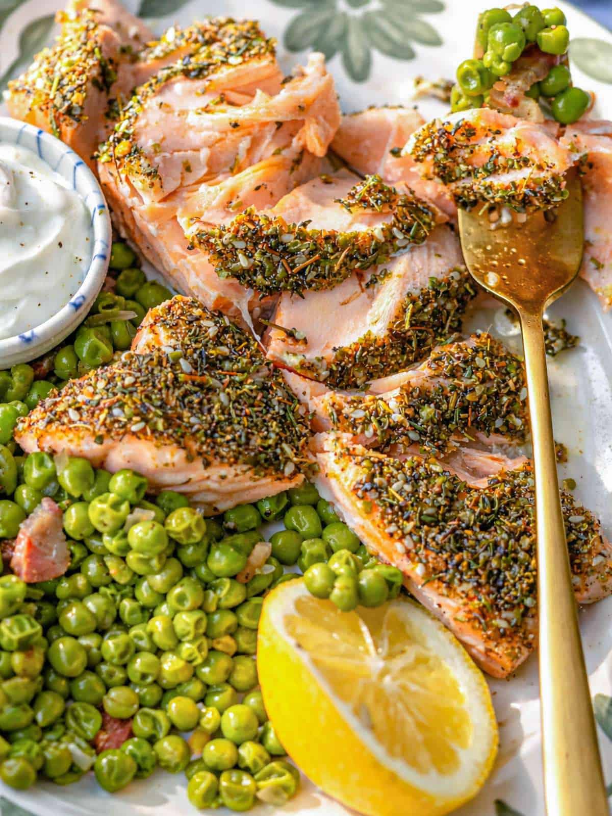 Roasted zaatar salmon on a plate with sautéed peas, yogurt, and lemon.