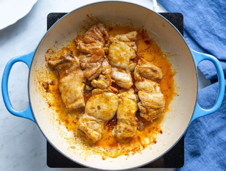 Step 1 Chicken thighs searing in olive oil until golden on both sides in a wide skillet.
