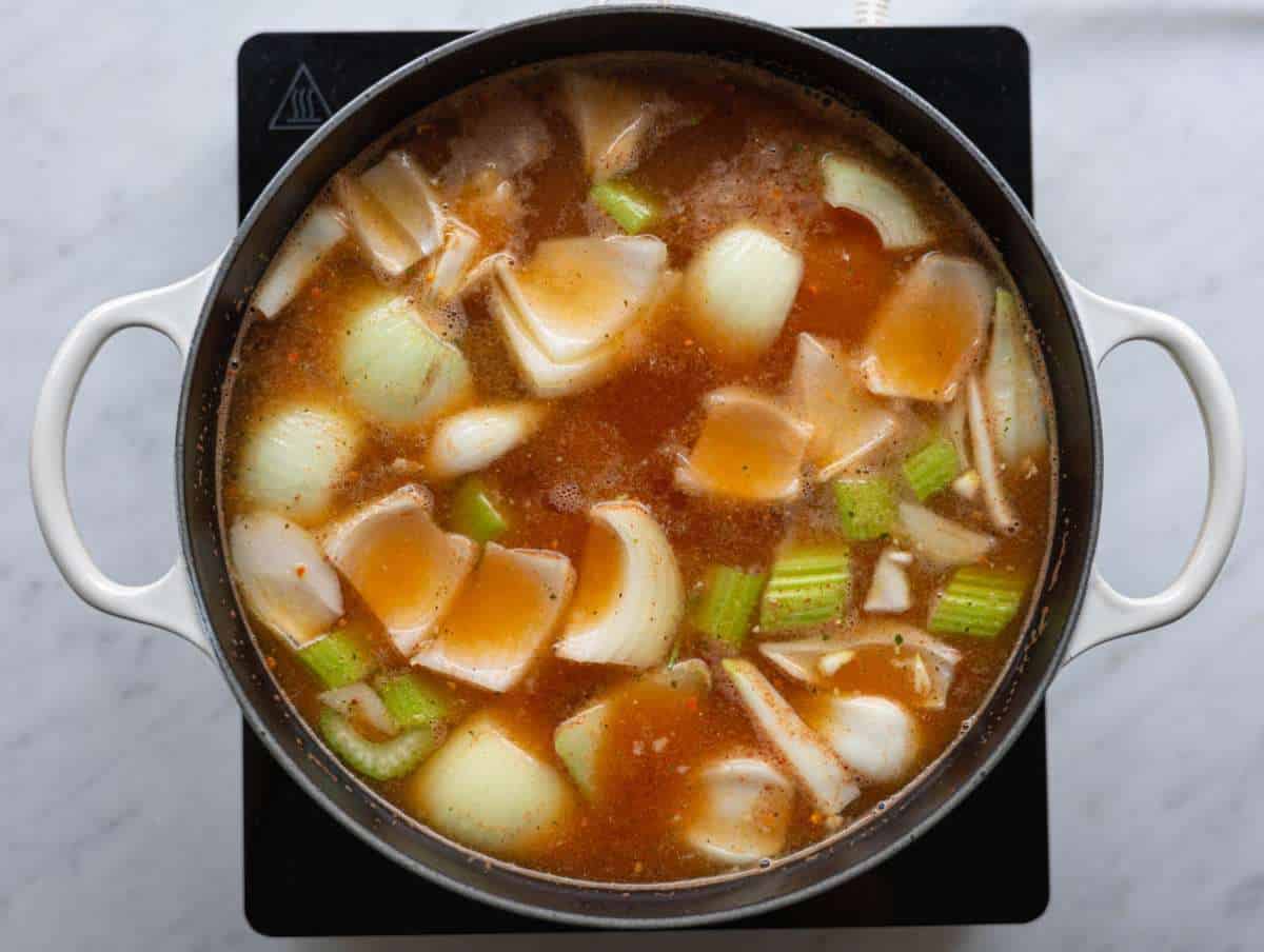 Step 1 Cold chicken broth in a pot with onion, carrots, celery, bay leaf, and Parmesan rind.