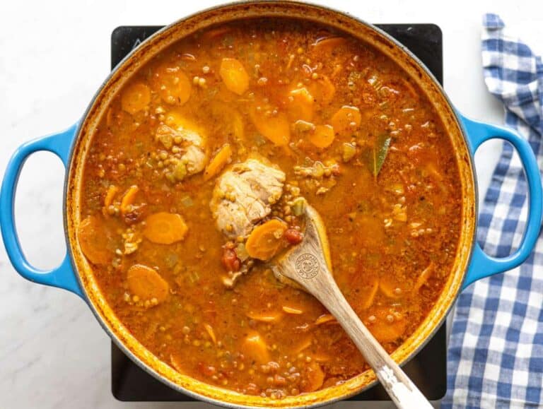 Step 2 Lentils, tomatoes, broth, and chicken thighs simmering together in a pot.