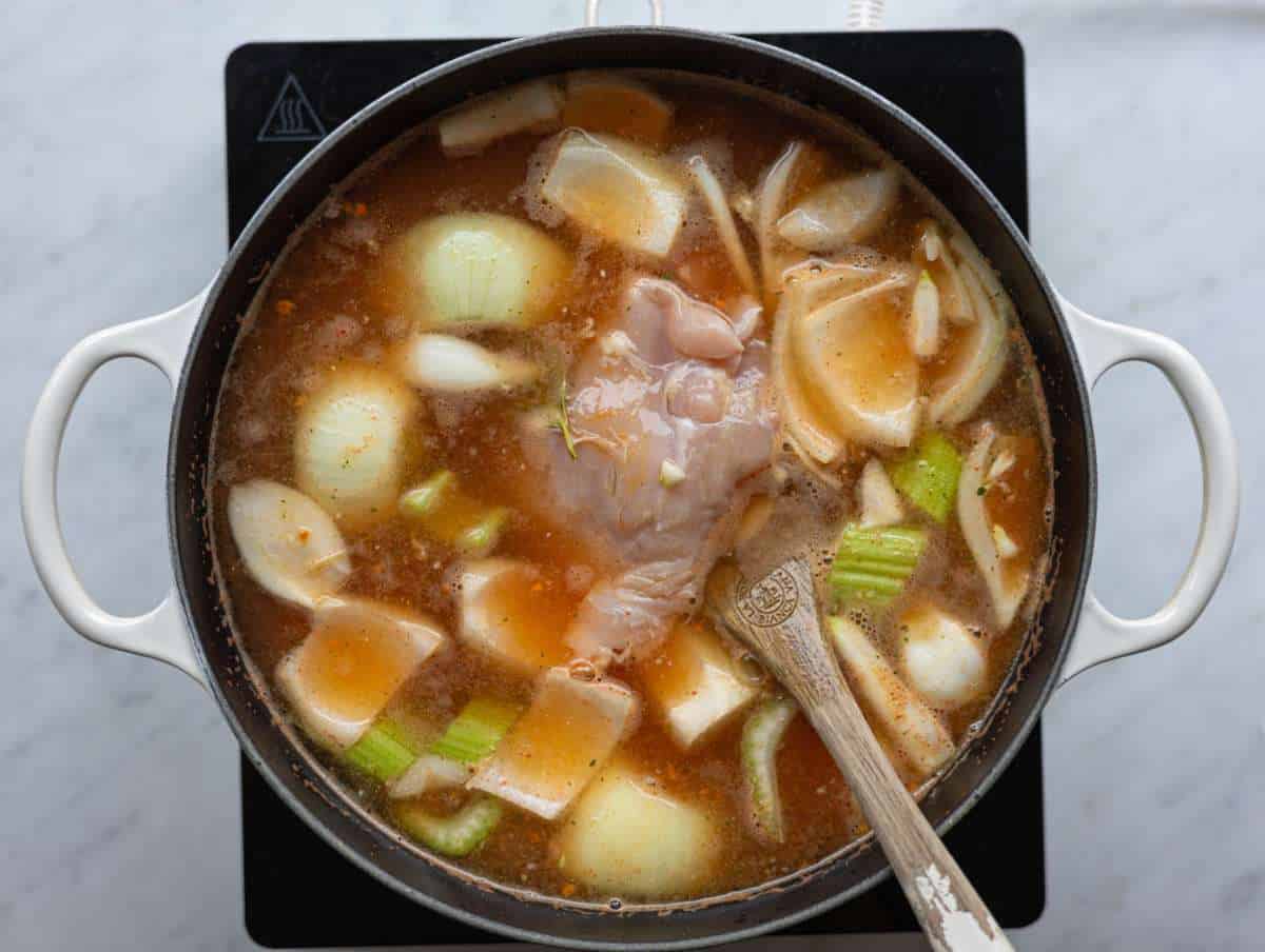 Step 2 Raw chicken gently simmering in broth with vegetables cooking until tender.