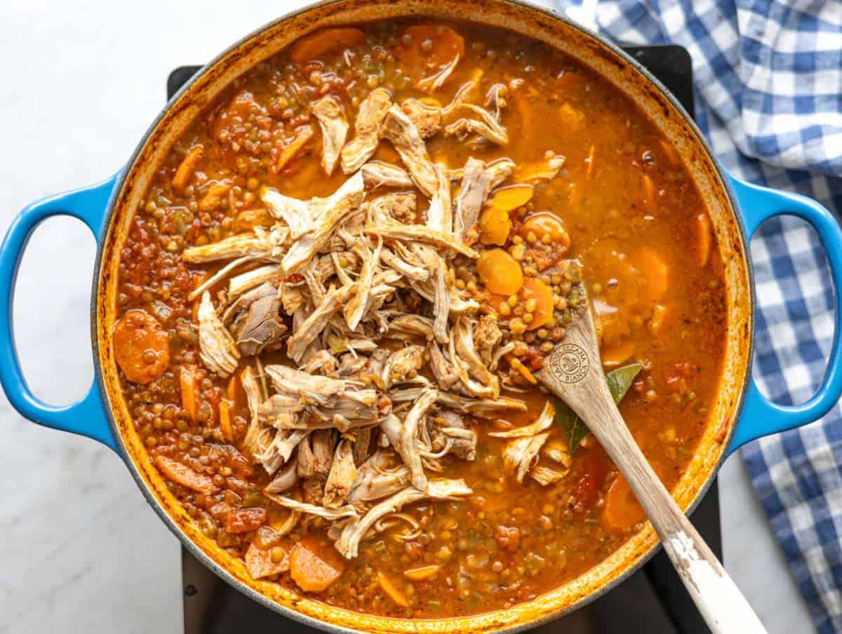 Step 3 Shredded chicken being pulled apart with fork and added back to soup.