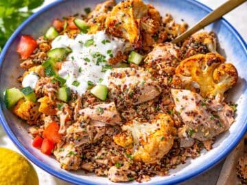Step 5 Salmon quinoa bowl served with roasted cauliflower, flaked salmon, fresh cucumber, tomato, and creamy sauce.