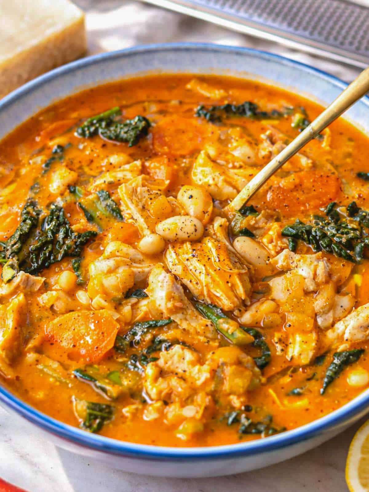Bowl of creamy chicken and white bean soup with kale, beans, and shredded chicken.