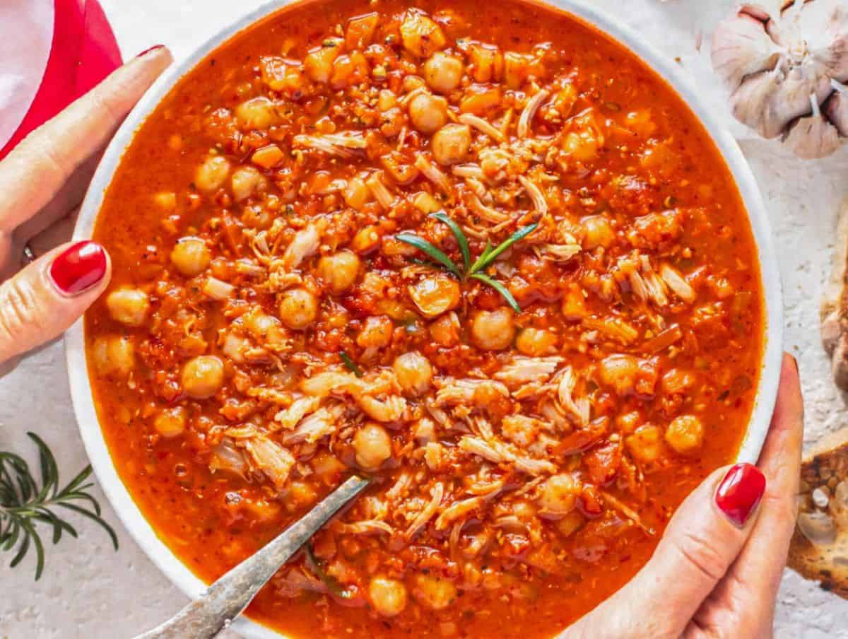 Hearty chicken chickpea soup served with crusty bread on a rustic table.