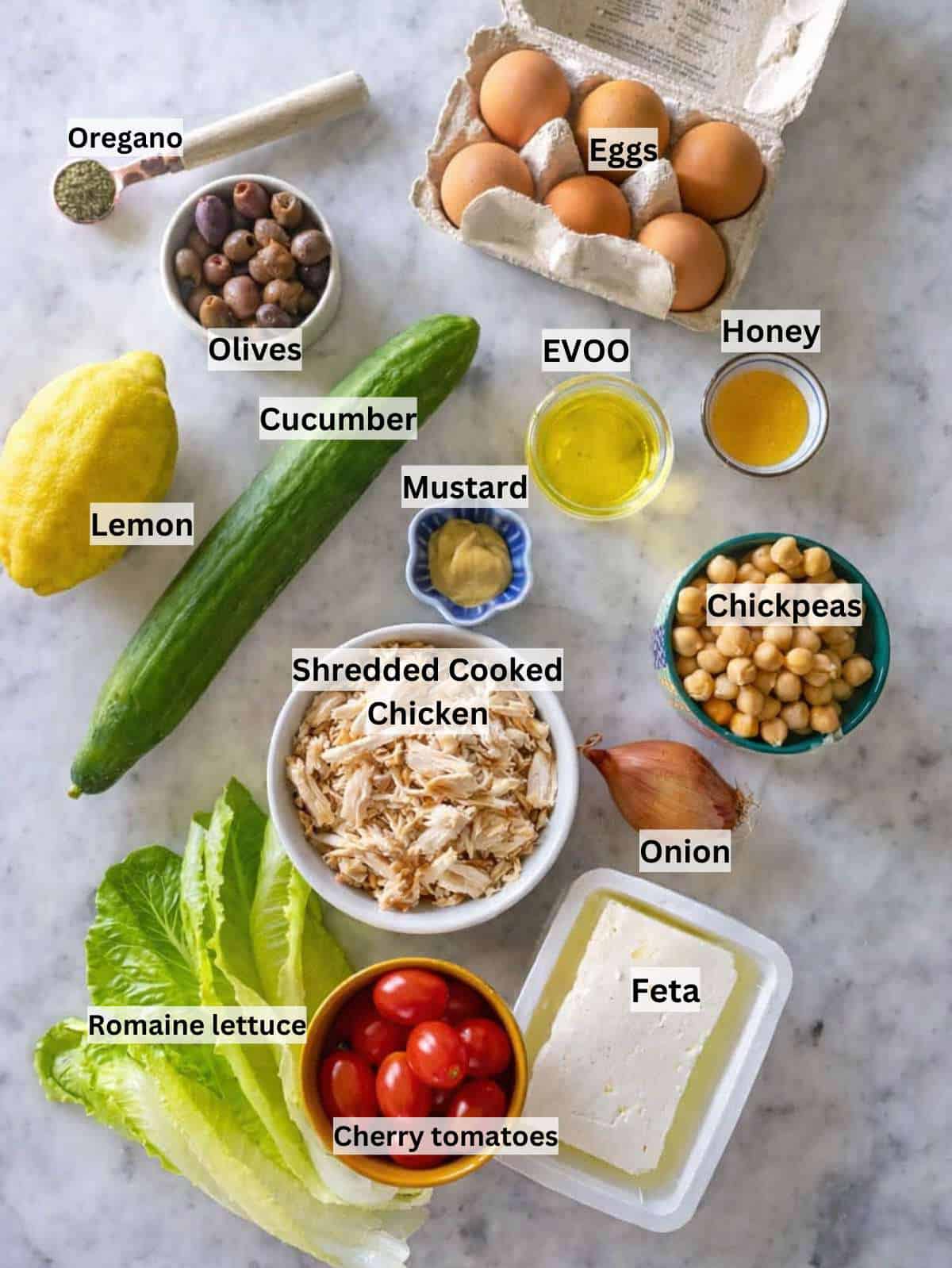 Ingredients for Mediterranean chopped chicken salad arranged on marble table.