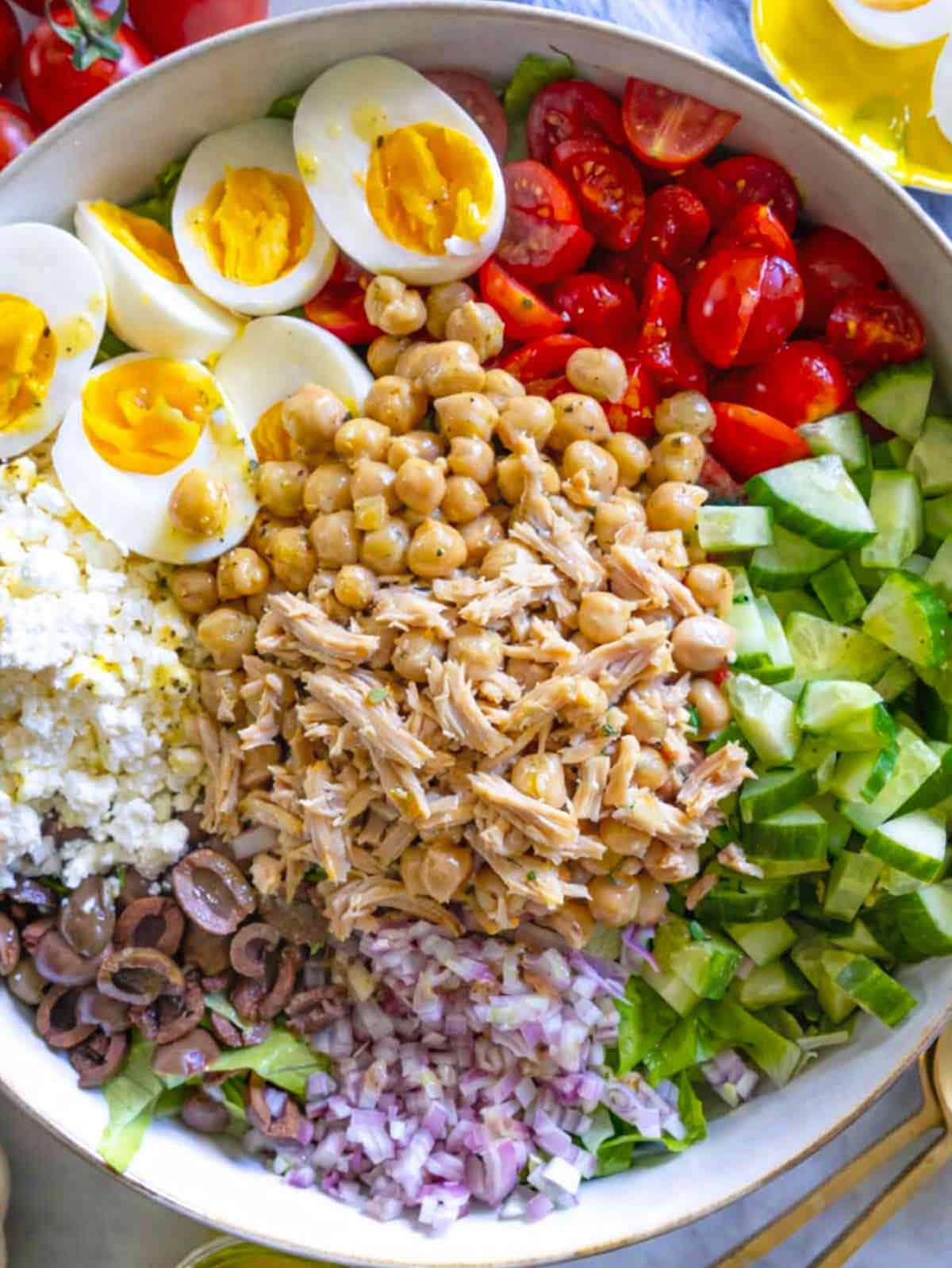 Large bowl of Mediterranean chopped chicken salad with eggs and feta.