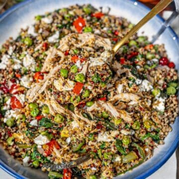 A balanced chicken quinoa bowl served in a ceramic dish on a sunlit marble tabletop.
