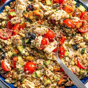 Bright bowl of quinoa salad with chicken and fresh vegetables.