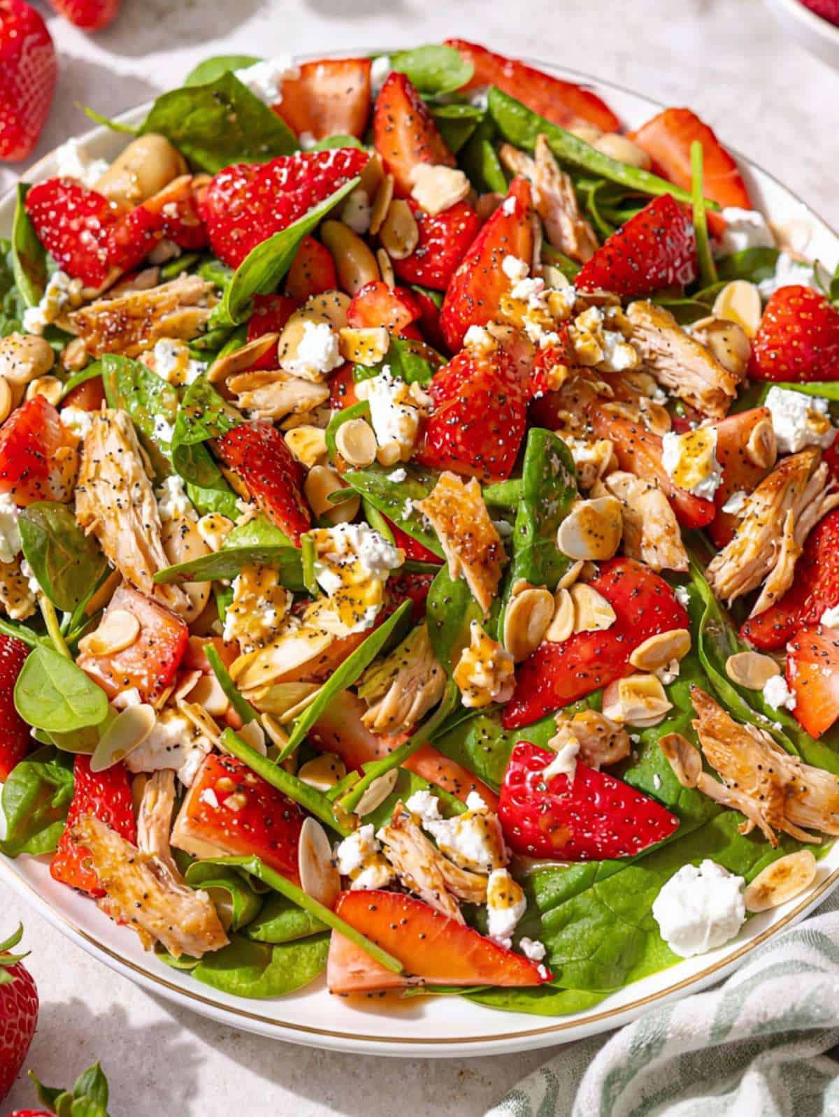 Close-up of strawberry spinach chicken salad with glossy dressing and juicy strawberries.