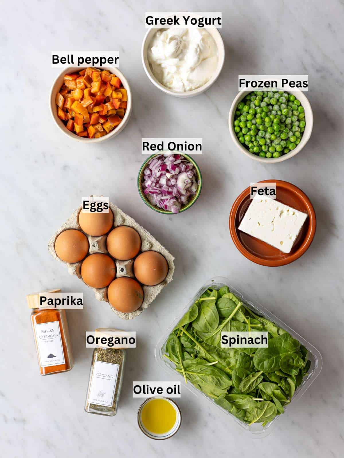Fresh eggs, a bowl of creamy Greek yogurt, and colorful chopped vegetables on white marble.