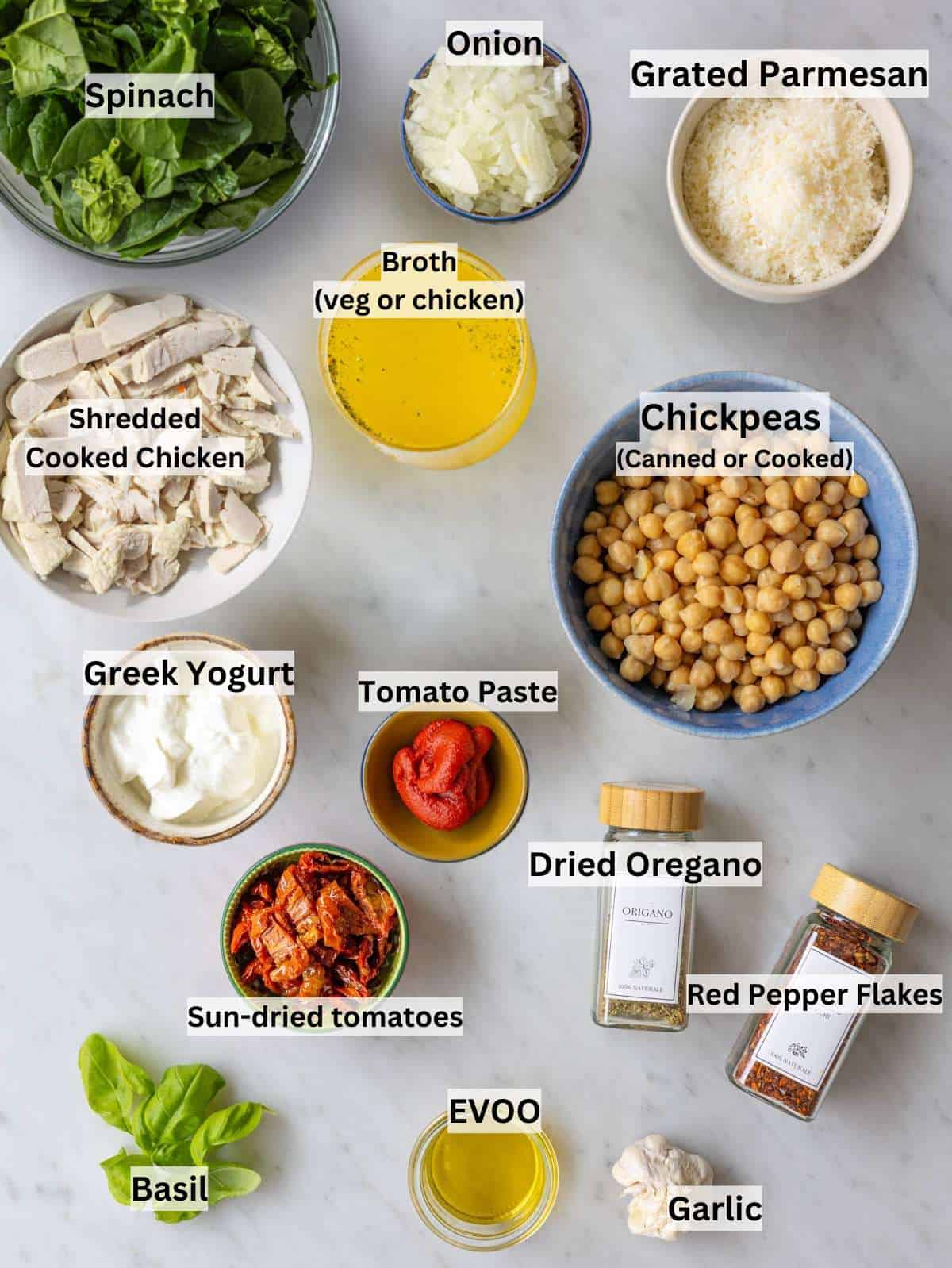 Fresh ingredients, shredded chicken, and cooked quinoa arranged neatly on a white marble surface.