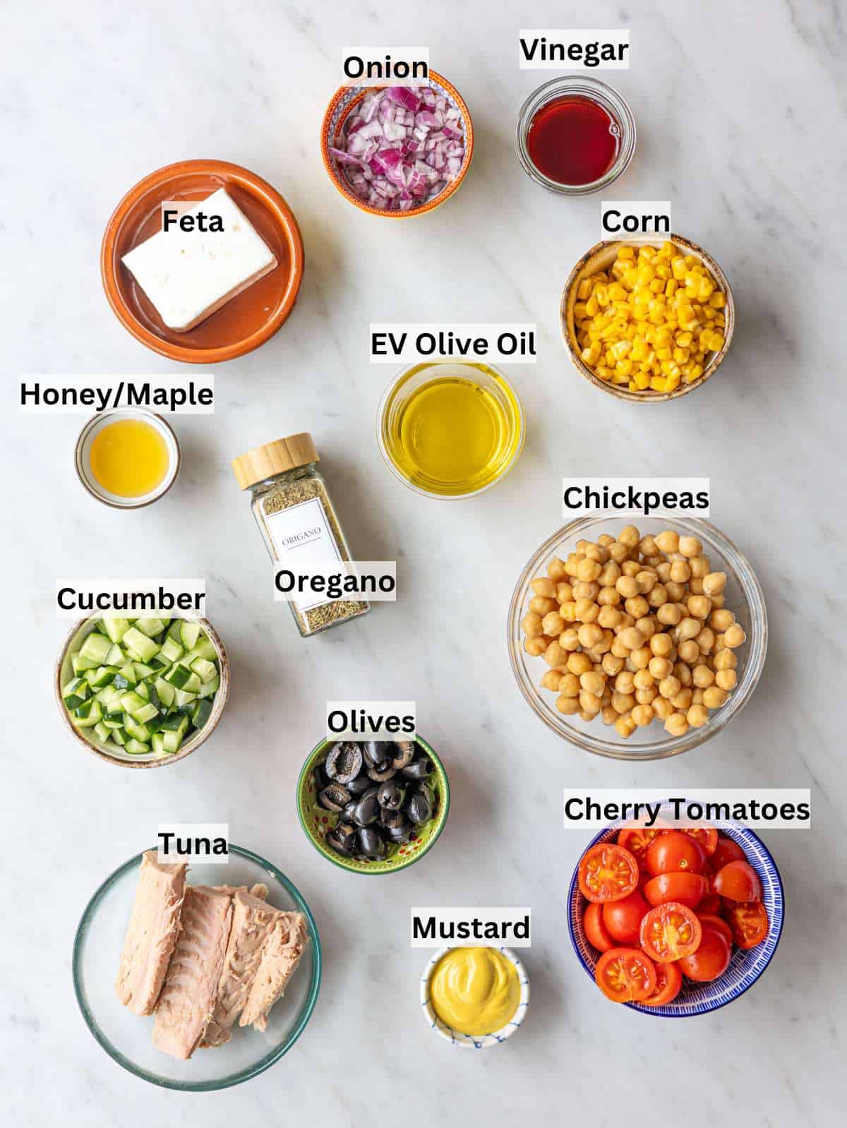 Ingredients for Mediterranean tuna chickpea salad arranged on marble table in natural window light.