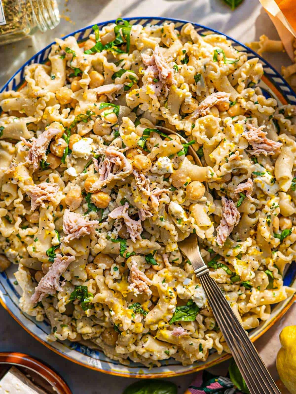 Lemon tuna pasta salad in bowl with chickpeas, feta, and fresh herbs.