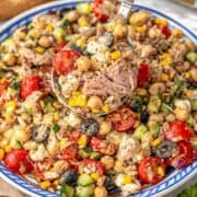 Mediterranean tuna chickpea salad in serving bowl on marble table with bright natural light.
