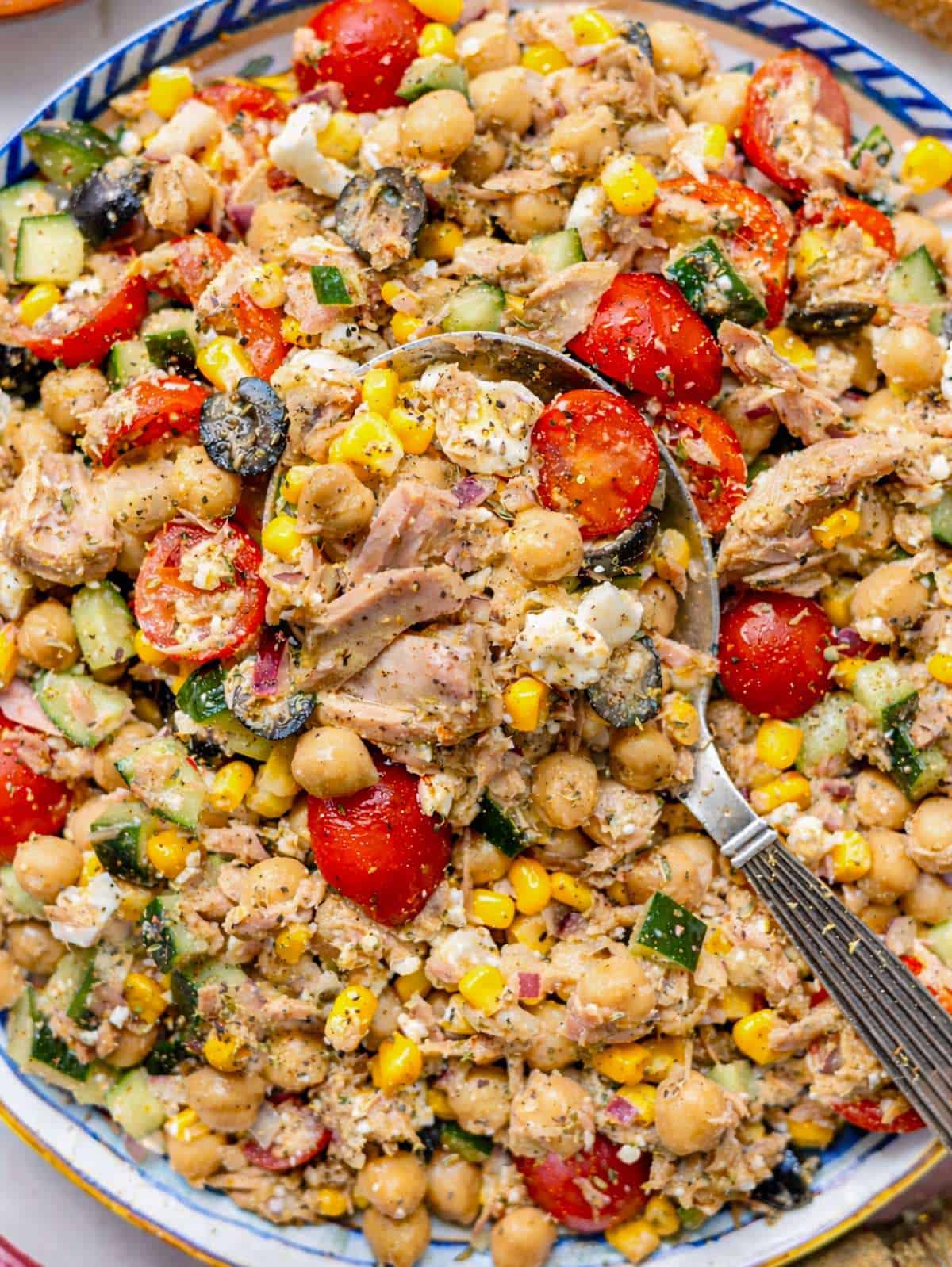 Mediterranean tuna chickpea salad with cucumbers tomatoes olives feta and parsley.
