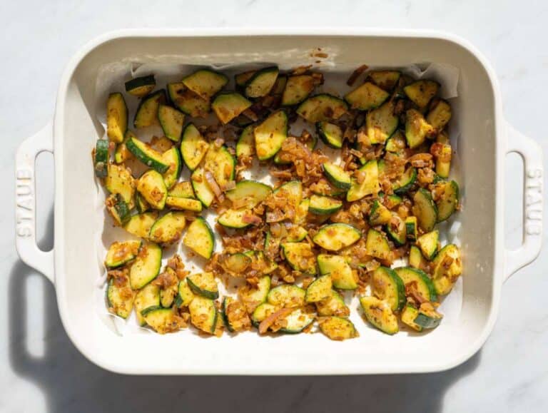 Step 1 Sautéed zucchini and red onions arranged in a baking pan on parchment.