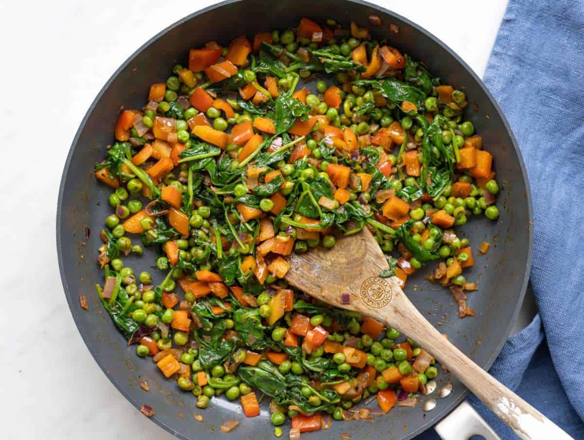 Step 1 Vibrant red peppers and spinach wilting in a skillet.