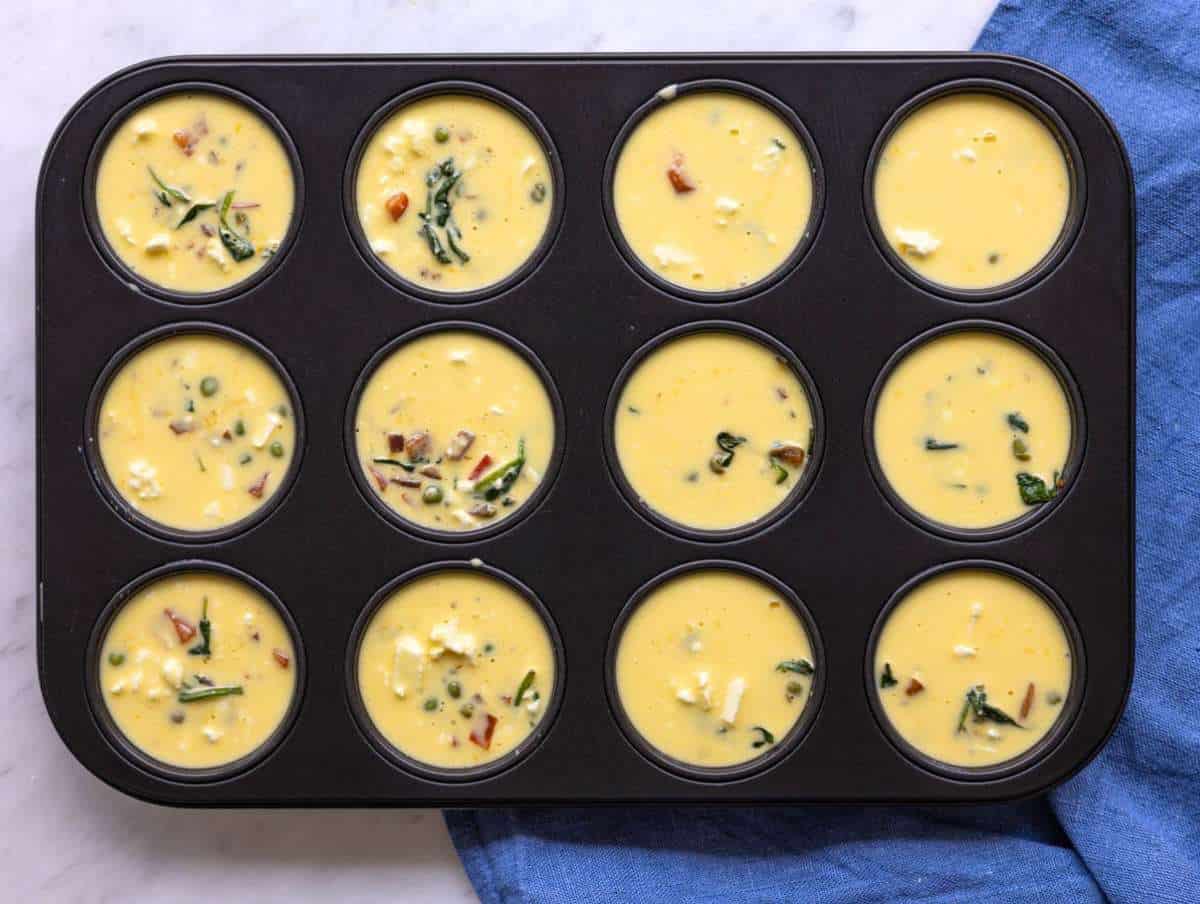 Step 4 Creamy egg mixture poured over colorful sautéed vegetables in a muffin tray.