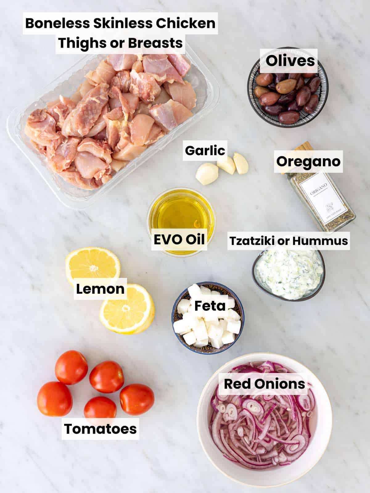 Fresh ingredients for Mediterranean chicken bowl on marble surface in soft natural window light.