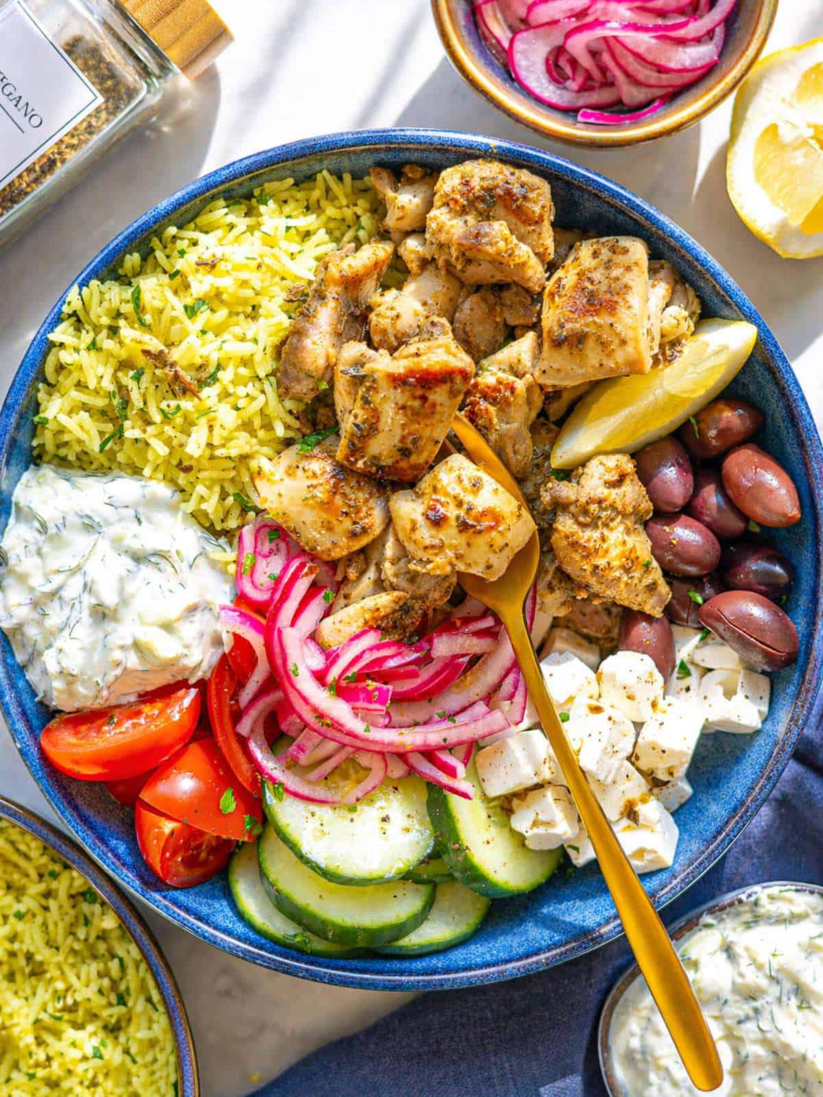 Mediterranean chicken bowl with rice, chicken, vegetables, and tzatziki in bright natural light.