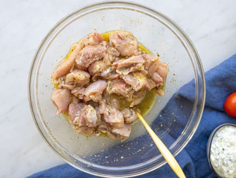 Step 1 Chicken pieces marinating in lemon garlic mixture in a bowl on marble surface.