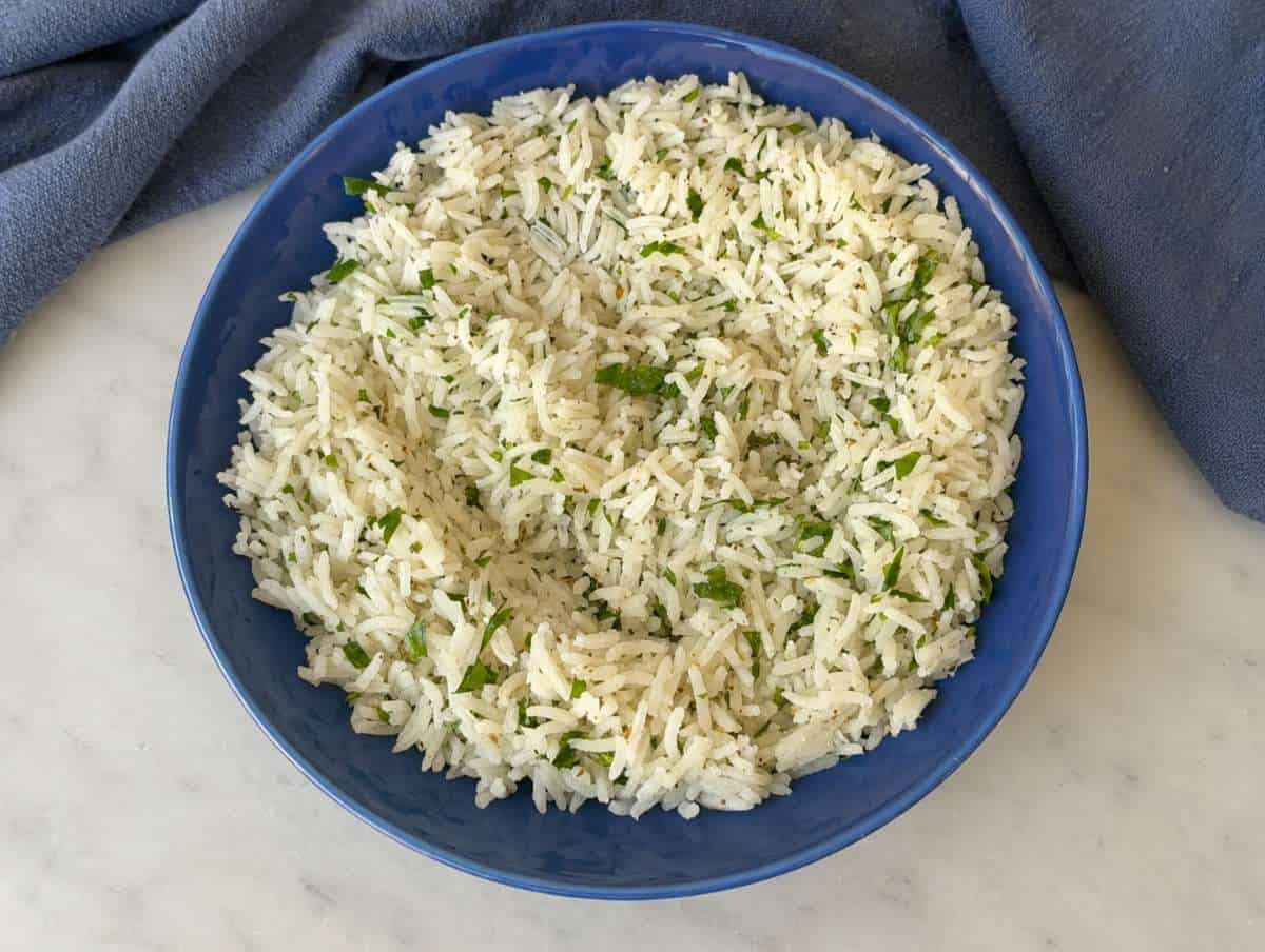 Step 1 Rice being tossed with olive oil, lemon, and herbs in a bowl on marble.