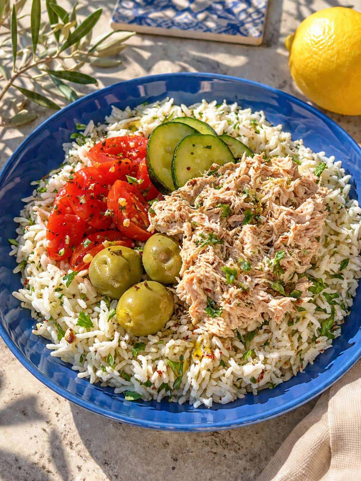 Tuna rice bowl with creamy tuna, fresh vegetables, and herbs in natural light.