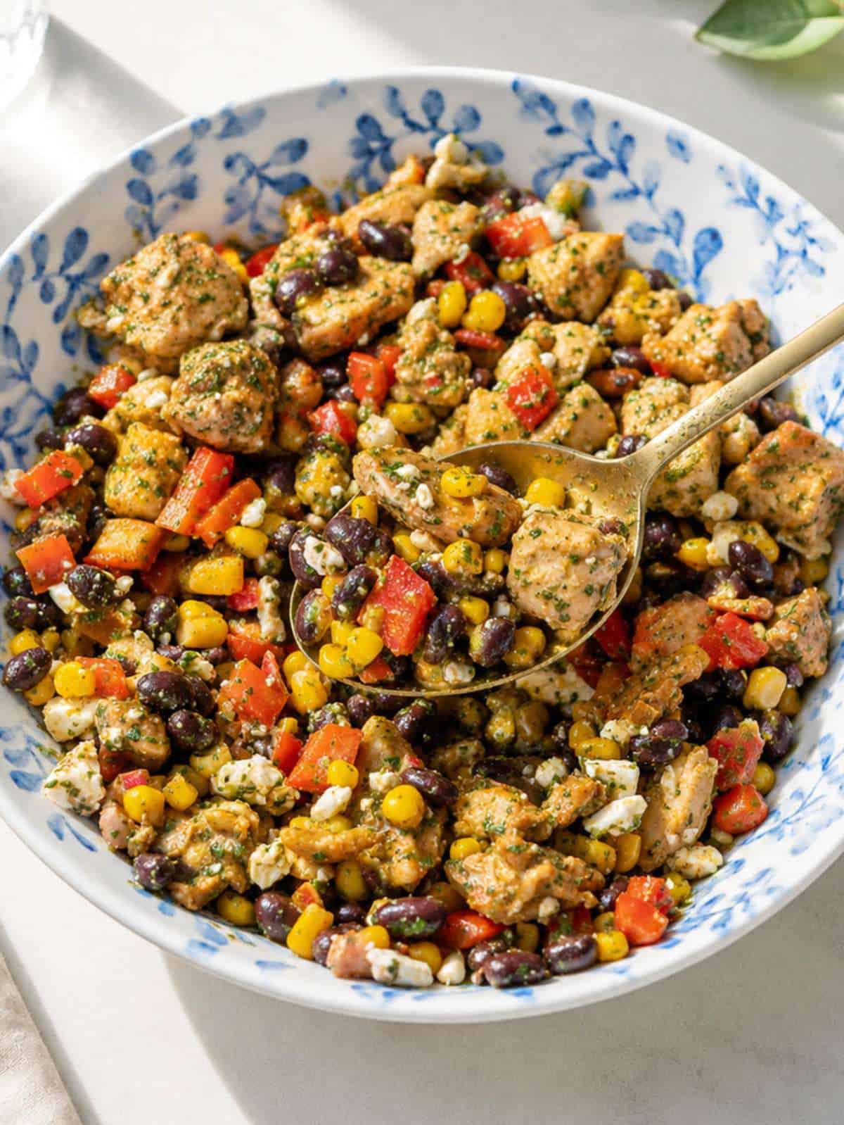 Chicken black bean salad with feta, cilantro, and lime dressing in serving bowl.