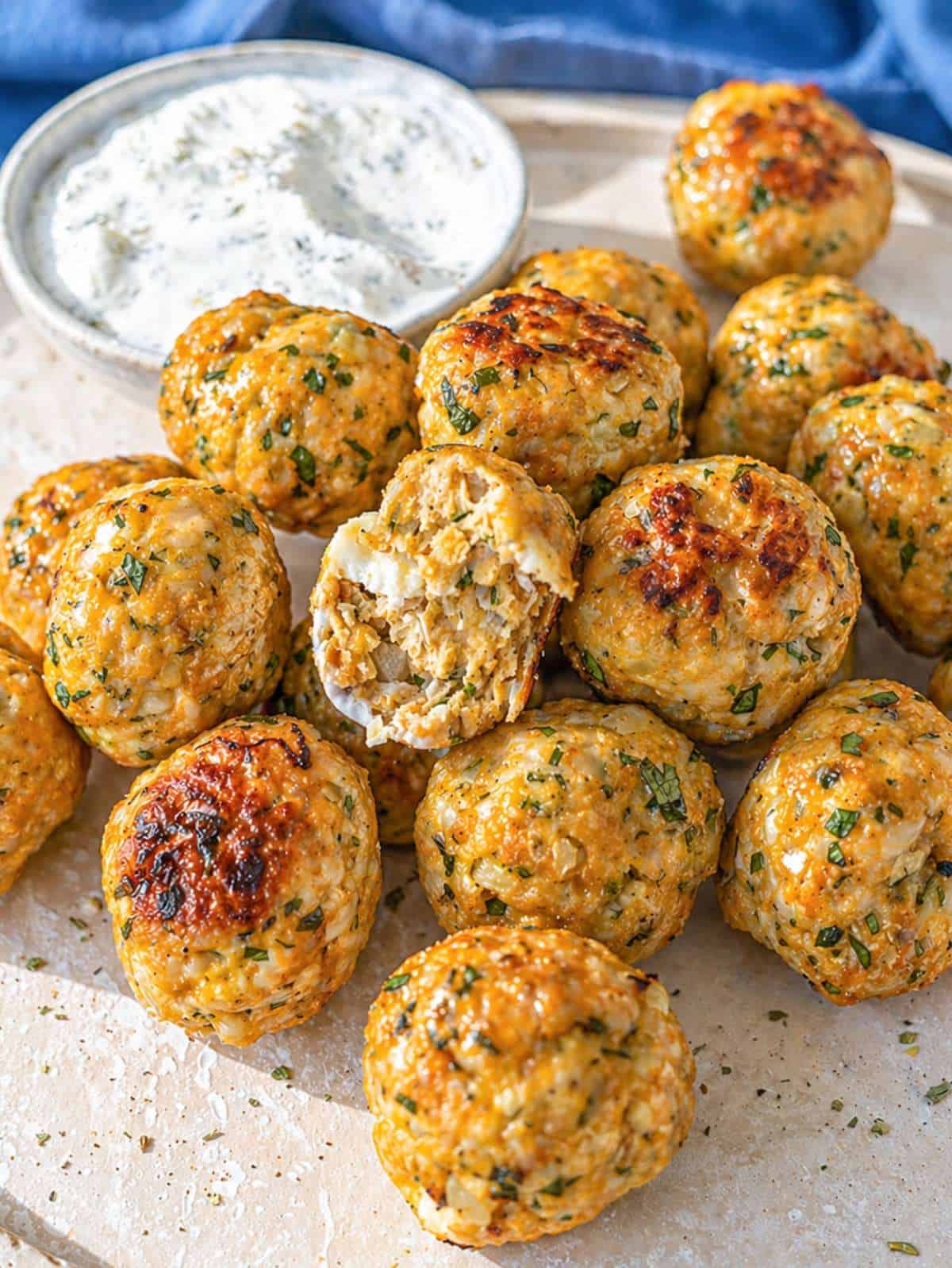 Close-up Greek turkey meatballs with creamy tzatziki and tender center on ceramic serving plate.
