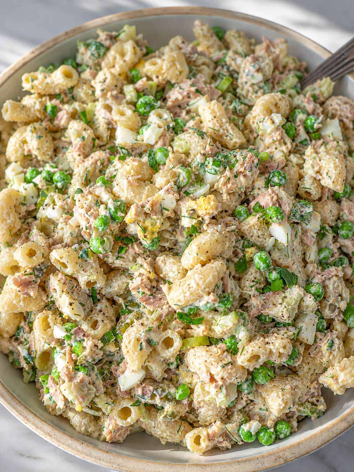 Close-up of tuna macaroni salad with Greek yogurt dressing, celery, and chopped pickles.