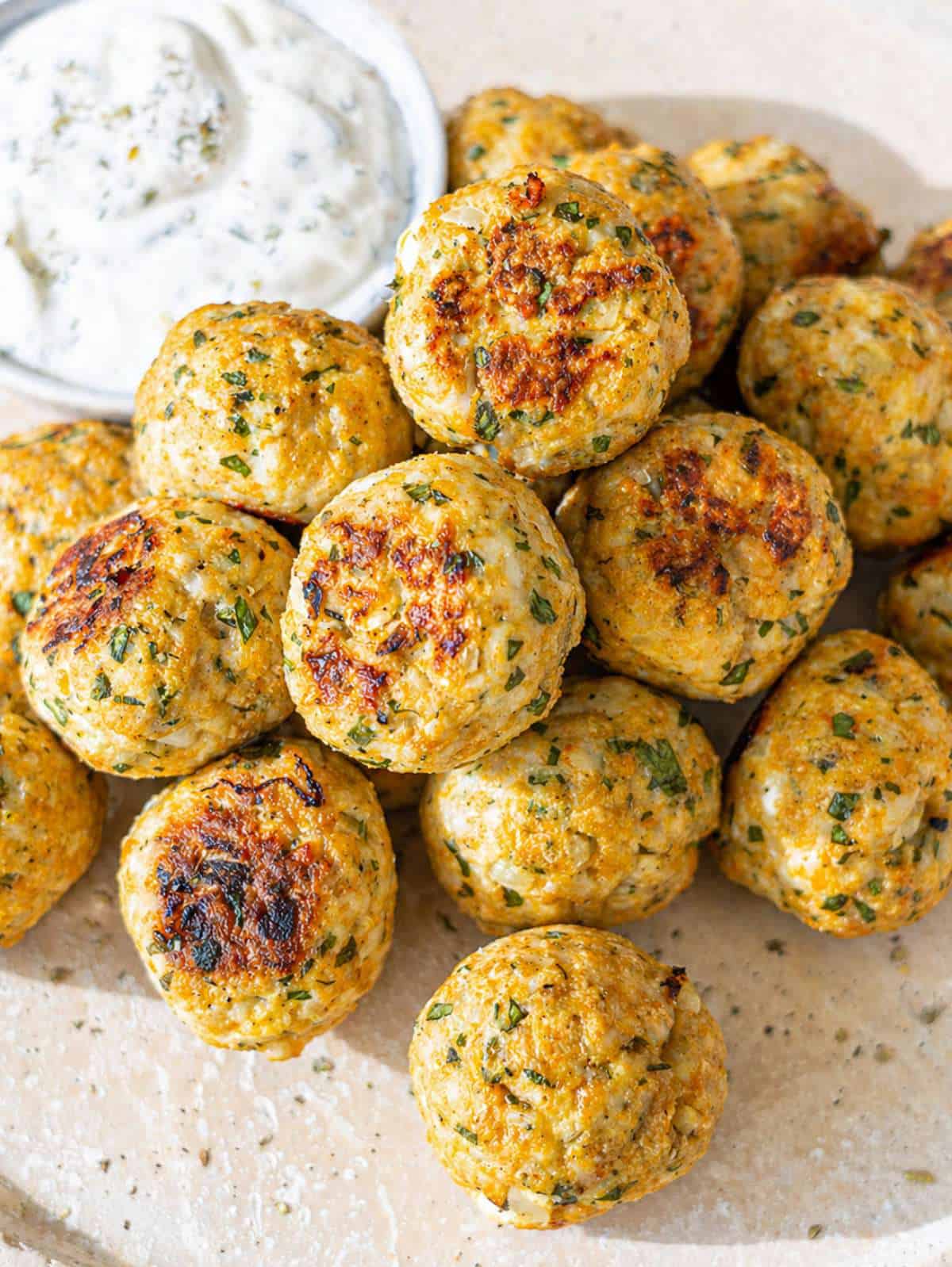 Golden Greek turkey meatballs with herbs and feta served beside creamy tzatziki dip.