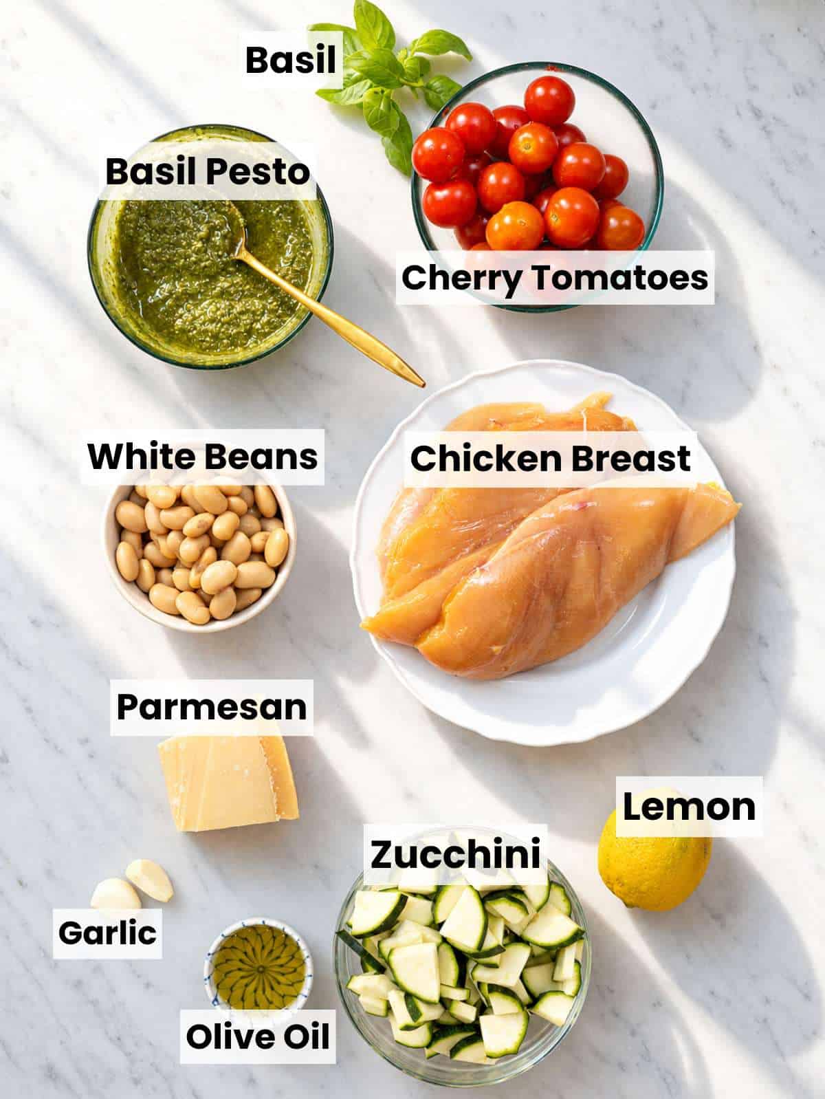 Ingredients for pesto chicken with zucchini, tomatoes, butter beans, lemon, and basil pesto.